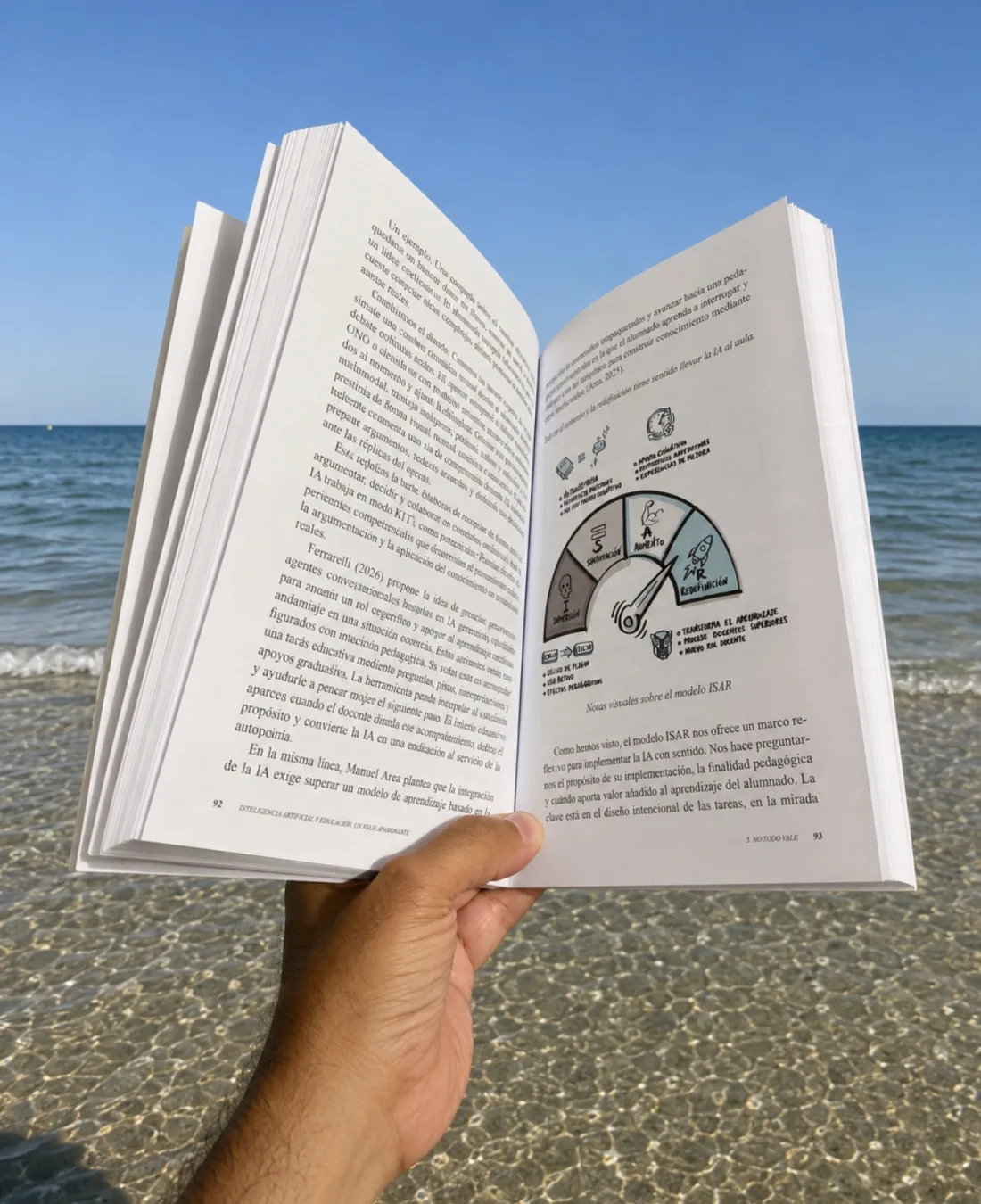 El libro abierto por una página con las notas visuales del modelo ISAR, sostenido en la mano frente a la orilla del mar
